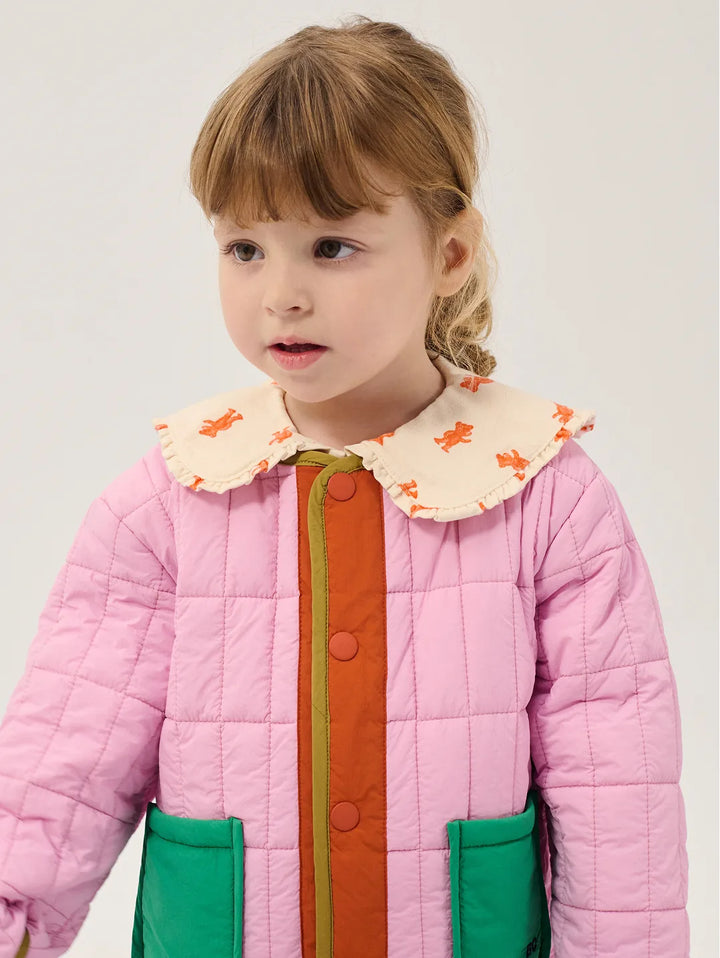 Child wearing a pink quilted jacket with a colorful collar on a plain background